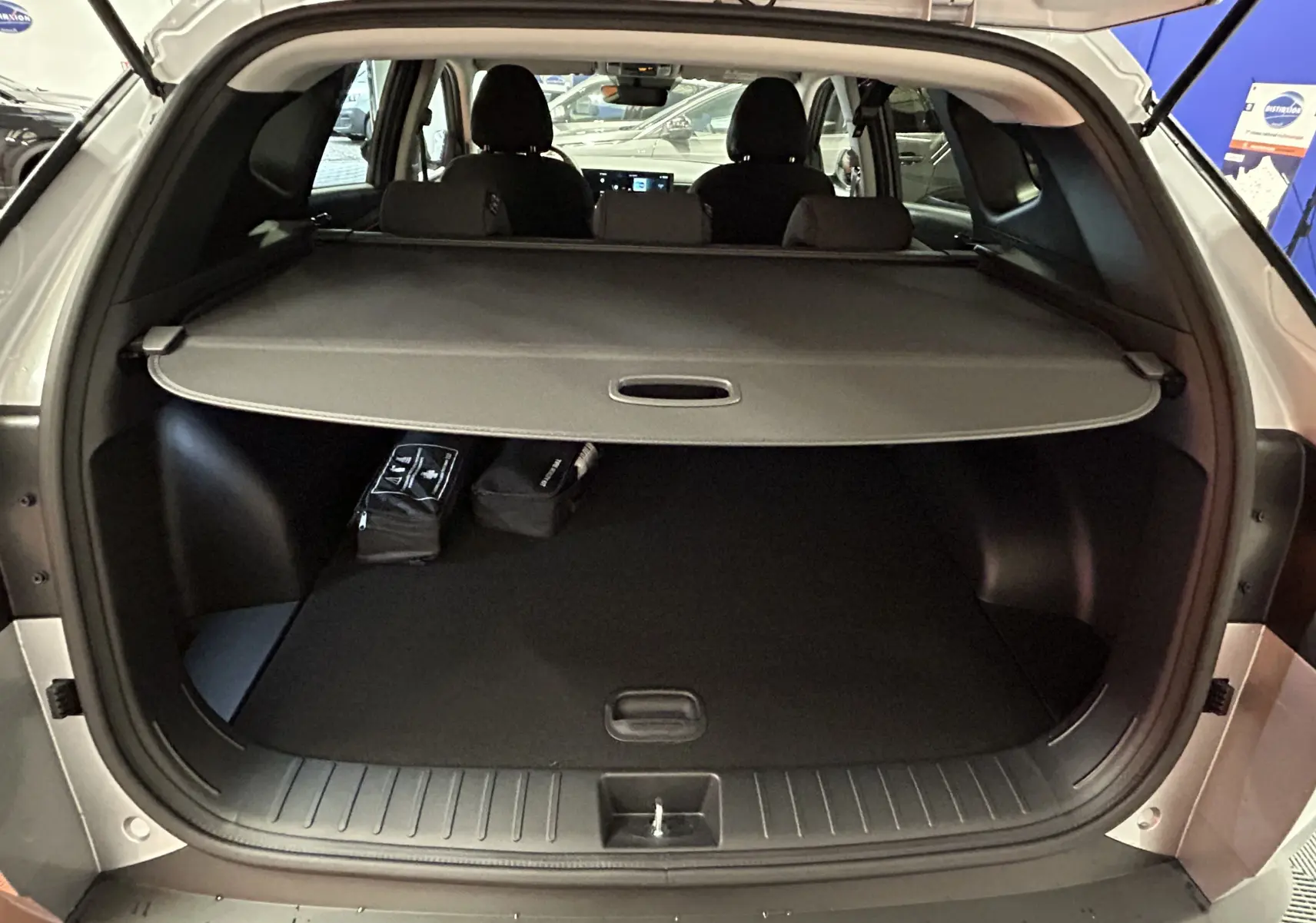 Coffre ouvert d'un Hyundai Tucson 2025 Shimmering Silver, vue arrière montrant la plage arrière et l'espace de chargement noir.