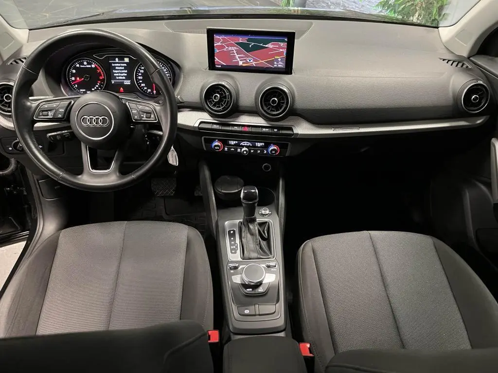 Vue intérieure avant de l'Audi Q2 2022 noir, avec tableau de bord, volant cuir multifonction et écran navigation central.