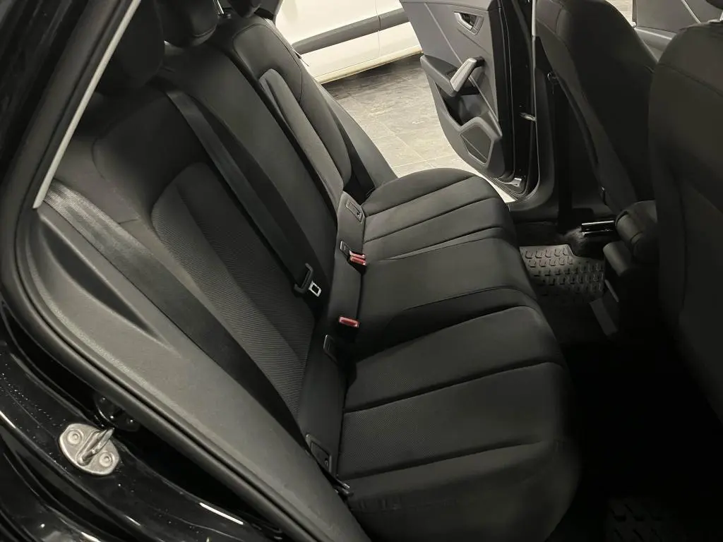 Vue intérieure arrière côté gauche de l'Audi Q2 2022 noire, montrant la banquette arrière en tissu noir et la portière ouverte.