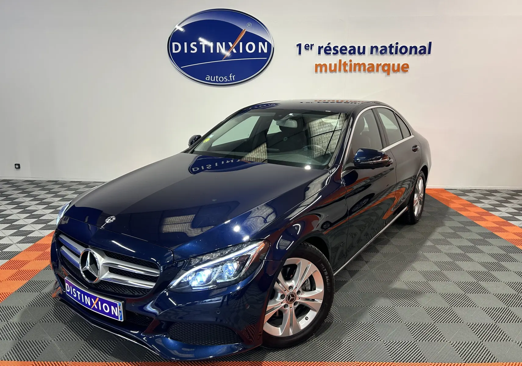 Mercedes Classe C 200d bleu en 3/4 avant droit, phares allumés, calandre chromée et jantes alliage visibles.