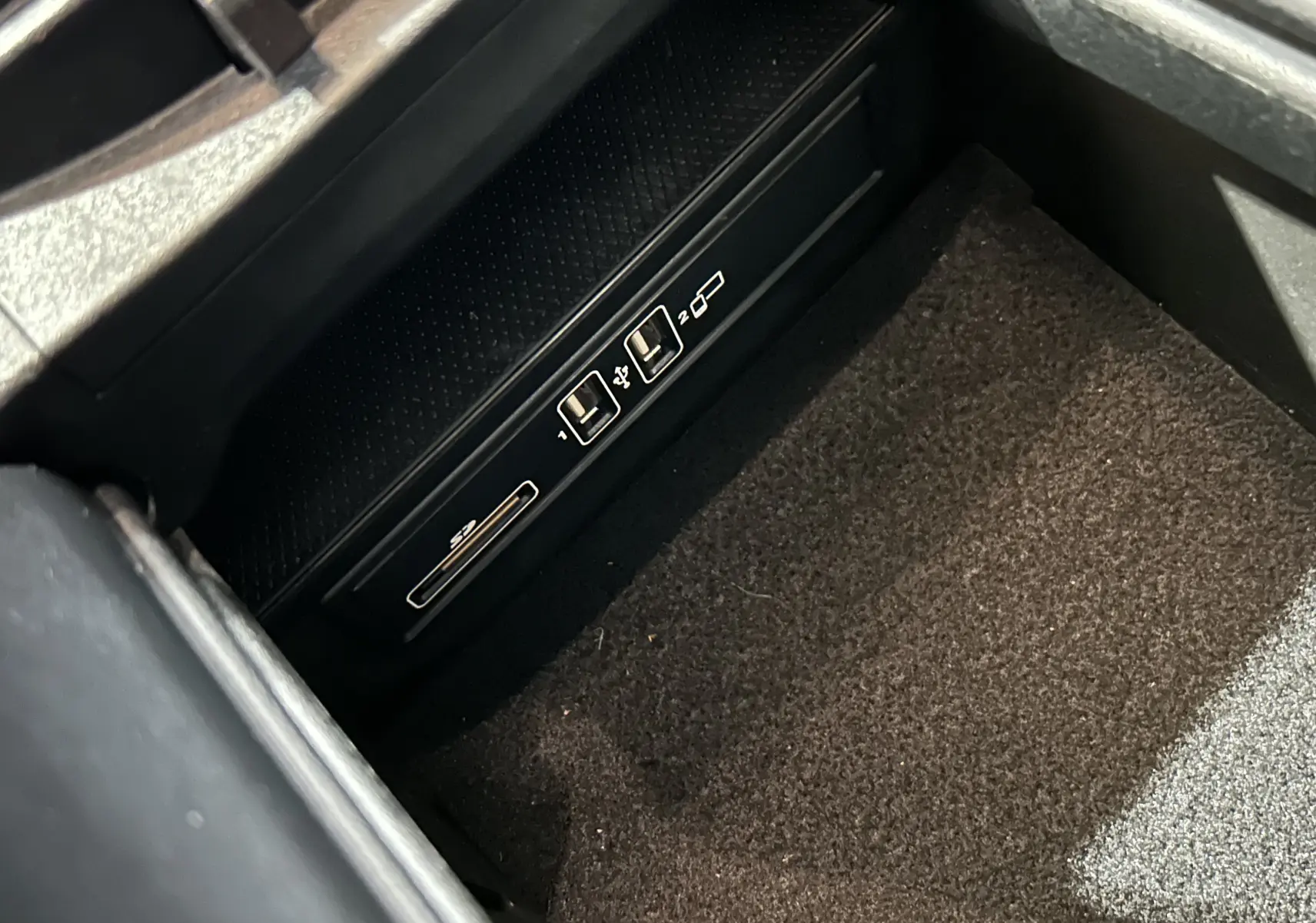 Gros plan sur les ports USB et lecteur de carte SD dans le compartiment central d'une Mercedes Classe C 200d bleue de 2018.