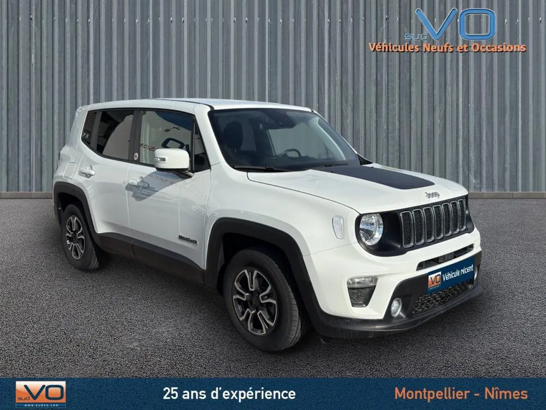 Jeep Renegade blanc en 3/4 avant droit avec capot noir et jantes alliage 17 pouces, stationné devant un mur métallique.