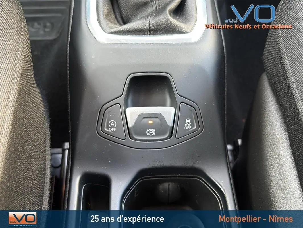 Gros plan sur la console centrale noire du Jeep Renegade blanc, mettant en valeur le frein à main électrique et la commande Start/Stop.