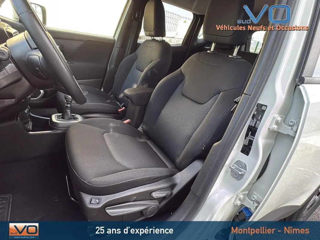 Intérieur avant droit du Jeep Renegade blanc 2020, sièges noirs avec accoudoir central et boîte manuelle visible.