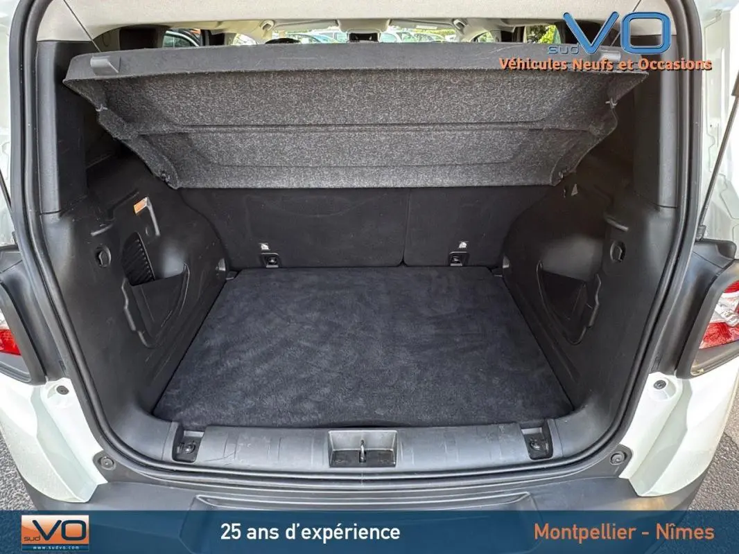 Coffre ouvert du Jeep Renegade blanc 2020, vue arrière montrant l'espace de chargement vide et la tablette cache-bagages relevée.