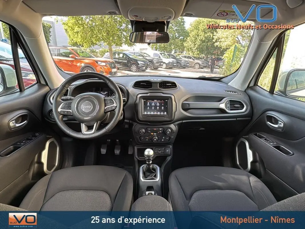 Vue intérieure avant du Jeep Renegade 2020 blanc, volant multifonction, écran tactile et boîte manuelle visibles.
