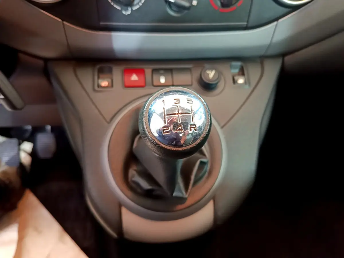 Gros plan sur le levier de vitesses manuel du Citroën Berlingo BlueHDi 75 BVM Feel, tableau de bord gris en arrière-plan.