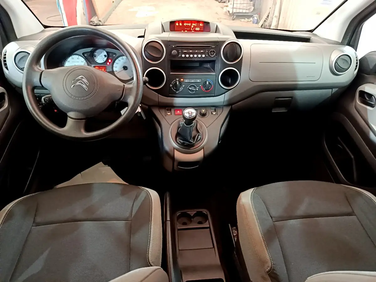 Vue intérieure avant du Citroën Berlingo 2016, tableau de bord gris avec volant et levier de vitesse manuel visibles.