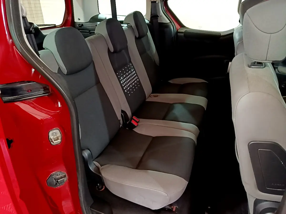Vue intérieure des sièges arrière bicolores gris et noir du Citroën Berlingo rouge, porte arrière ouverte côté gauche.