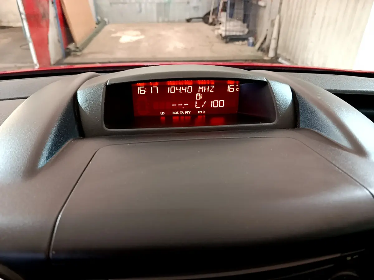 Affichage central du tableau de bord du Citroën Berlingo rouge, montrant l'heure, la température et la fréquence radio.