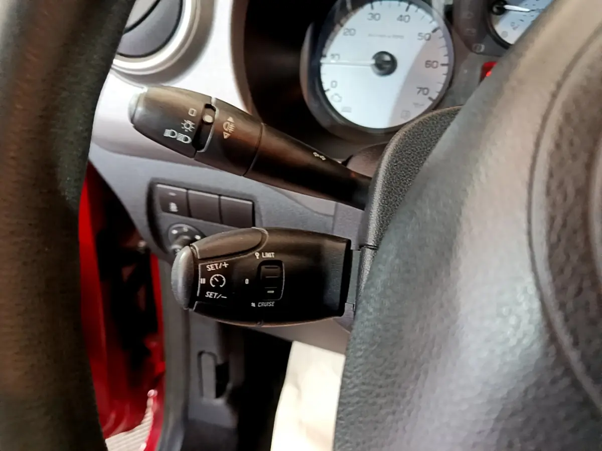 Gros plan sur les commandes de régulateur et feux du tableau de bord d'un Citroën Berlingo rouge côté gauche.