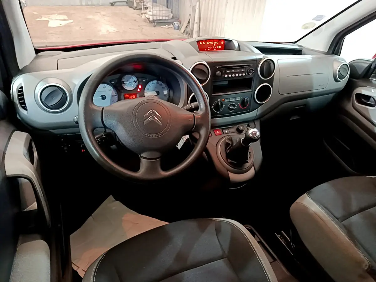 Vue intérieure avant du Citroën Berlingo 2016, tableau de bord gris avec volant noir et levier de vitesses manuel.