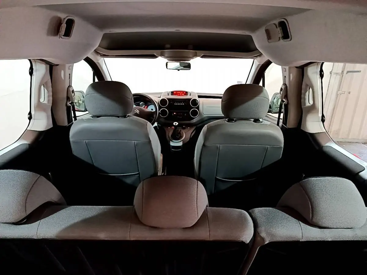 Vue intérieure arrière du Citroën Berlingo rouge 2016, montrant les sièges avant et le tableau de bord.