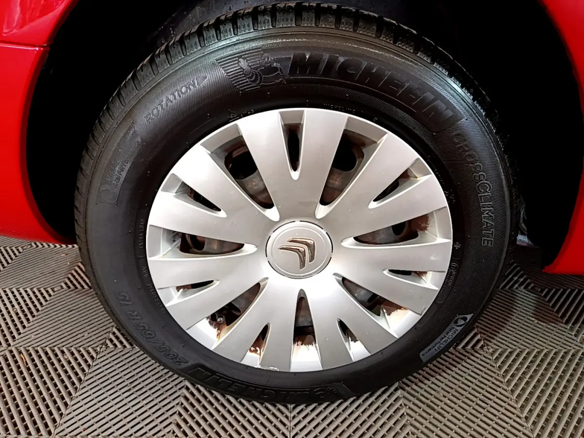 Gros plan sur la roue avant gauche rouge d’un Citroën Berlingo 2016 avec enjoliveur argenté et pneu Michelin.