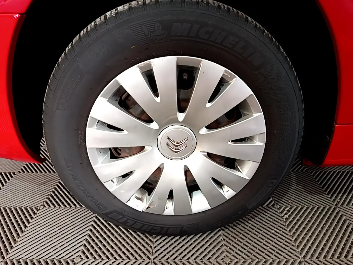 Gros plan sur la roue avant gauche rouge d’un Citroën Berlingo 2016 avec enjoliveur argenté et pneu Michelin.