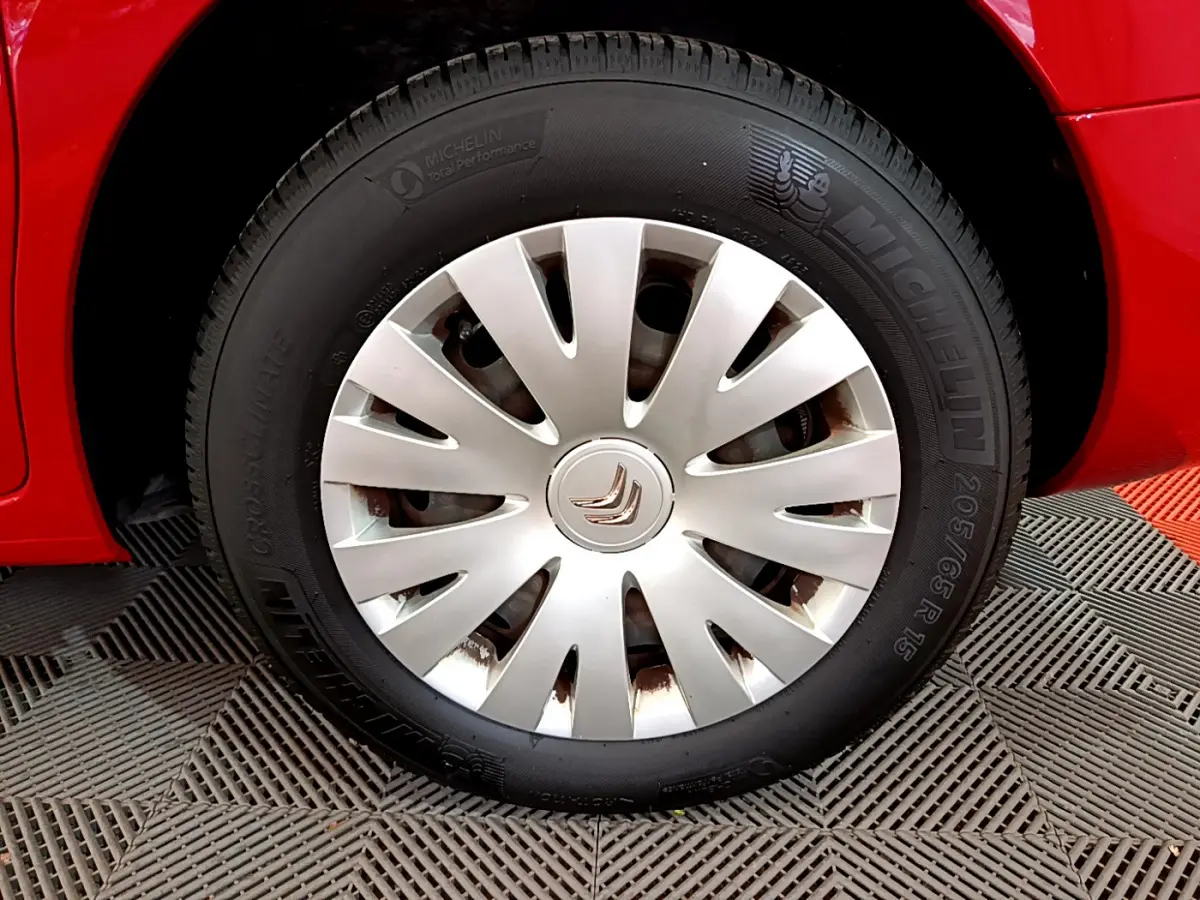 Gros plan sur la roue avant droite rouge d’un Citroën Berlingo 2016 avec enjoliveur argenté et pneu Michelin.