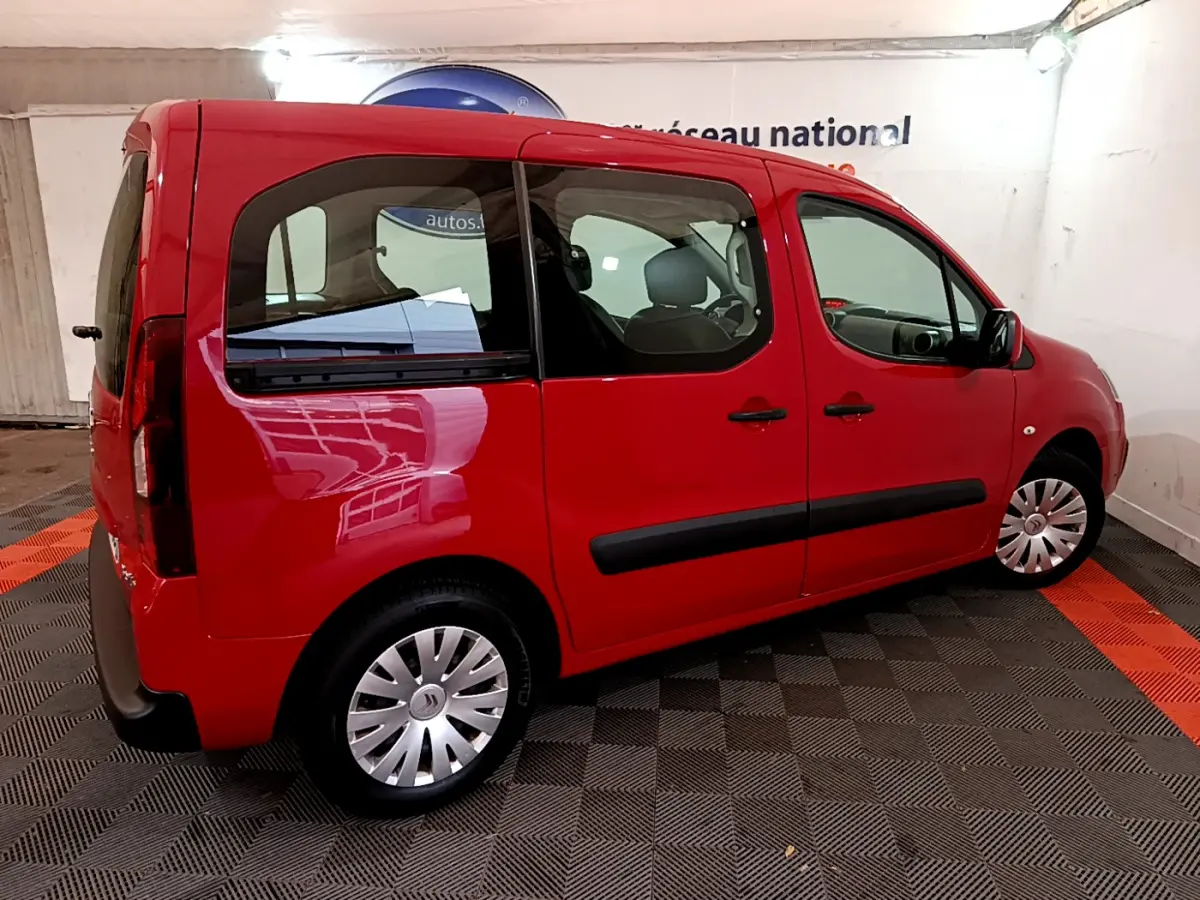 Vue 3/4 arrière côté gauche d'un Citroën Berlingo rouge 2016 avec vitres teintées et jantes acier à enjoliveurs.