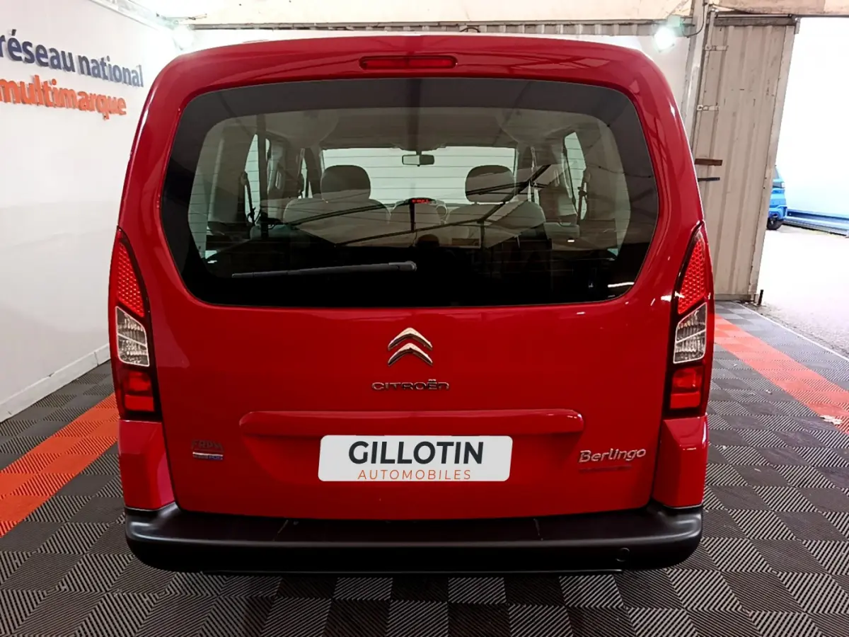 Vue arrière d'un Citroën Berlingo rouge 2016 avec hayon vitré et logo visible sur fond d'intérieur showroom.