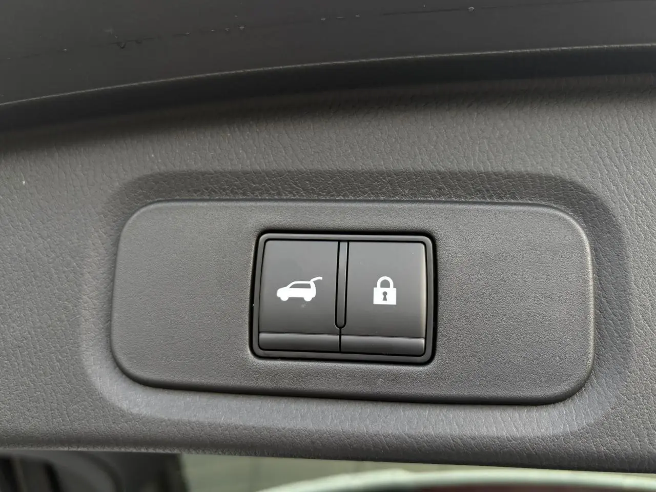 Boutons d'ouverture électrique du hayon et de verrouillage sur panneau intérieur du Nissan Qashqai blanc nacré 2025.