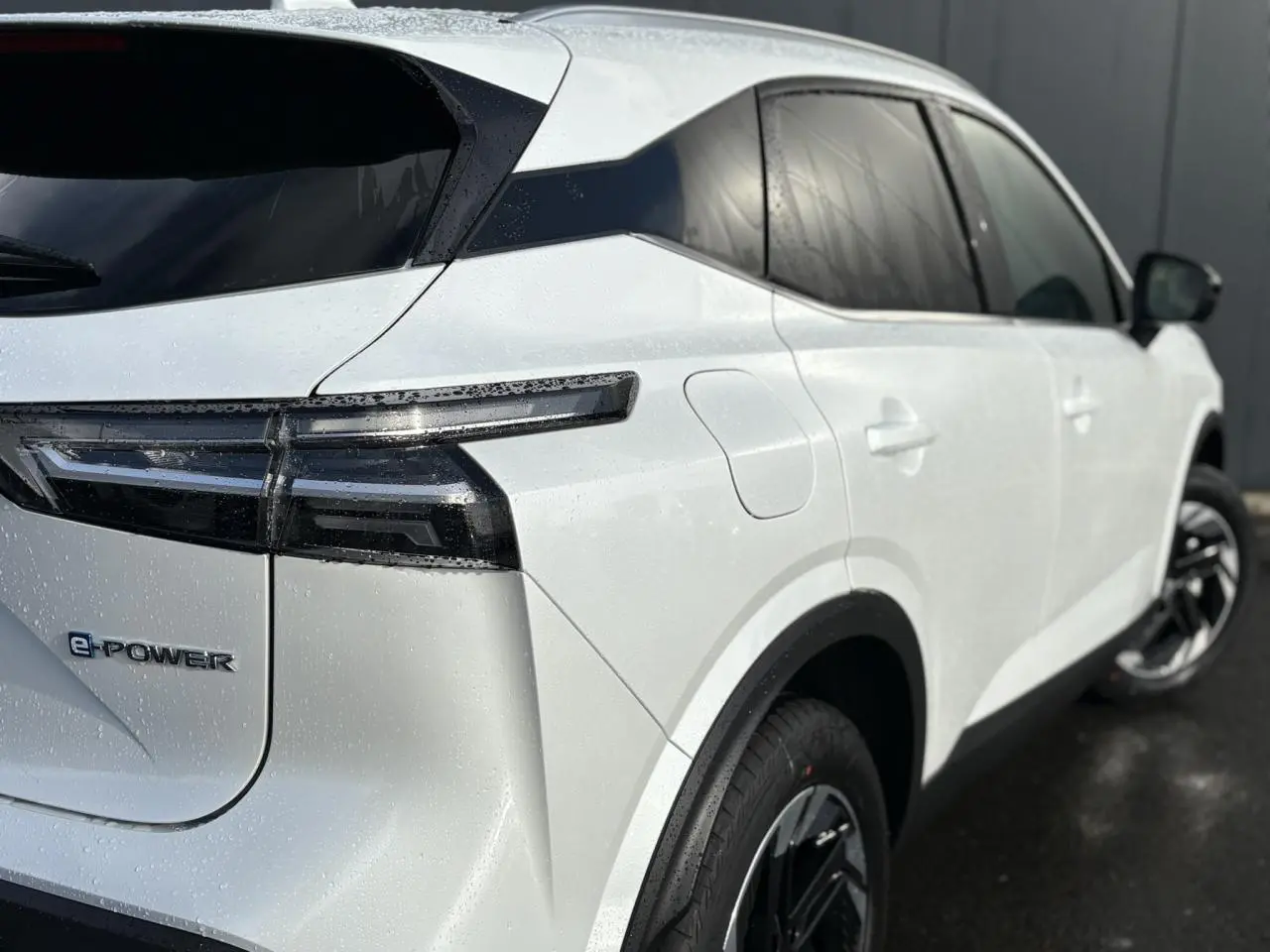 Vue 3/4 arrière droite du Nissan Qashqai blanc nacré e-Power avec feux arrière LED et jantes alliage 18 pouces.