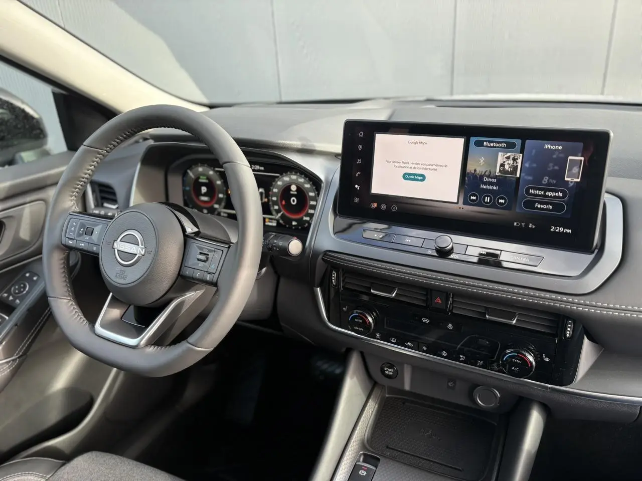 Vue intérieure côté conducteur du Nissan Qashqai blanc nacré 2025, avec tableau de bord numérique et écran tactile central.