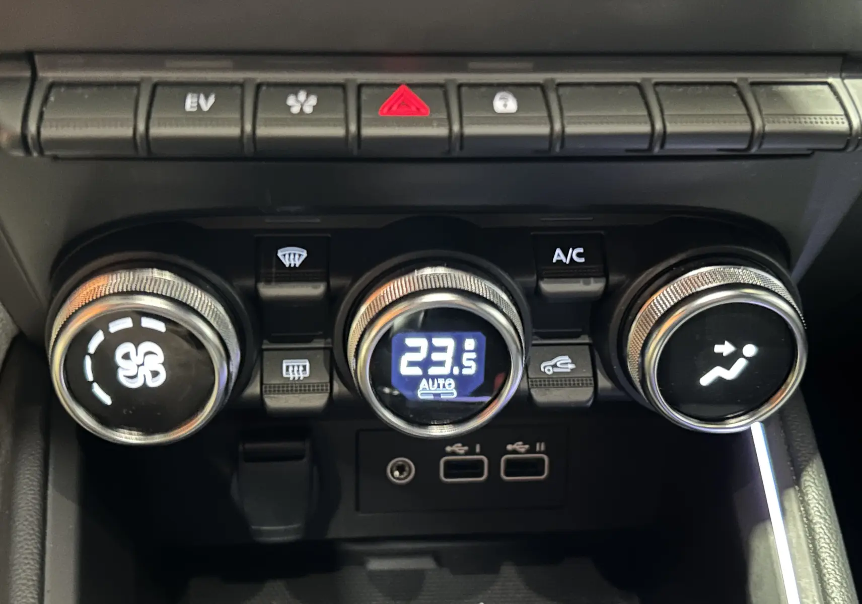 Gros plan sur la console centrale de la Renault Clio V E-Tech, montrant les commandes de climatisation digitales et boutons fonctionnels.