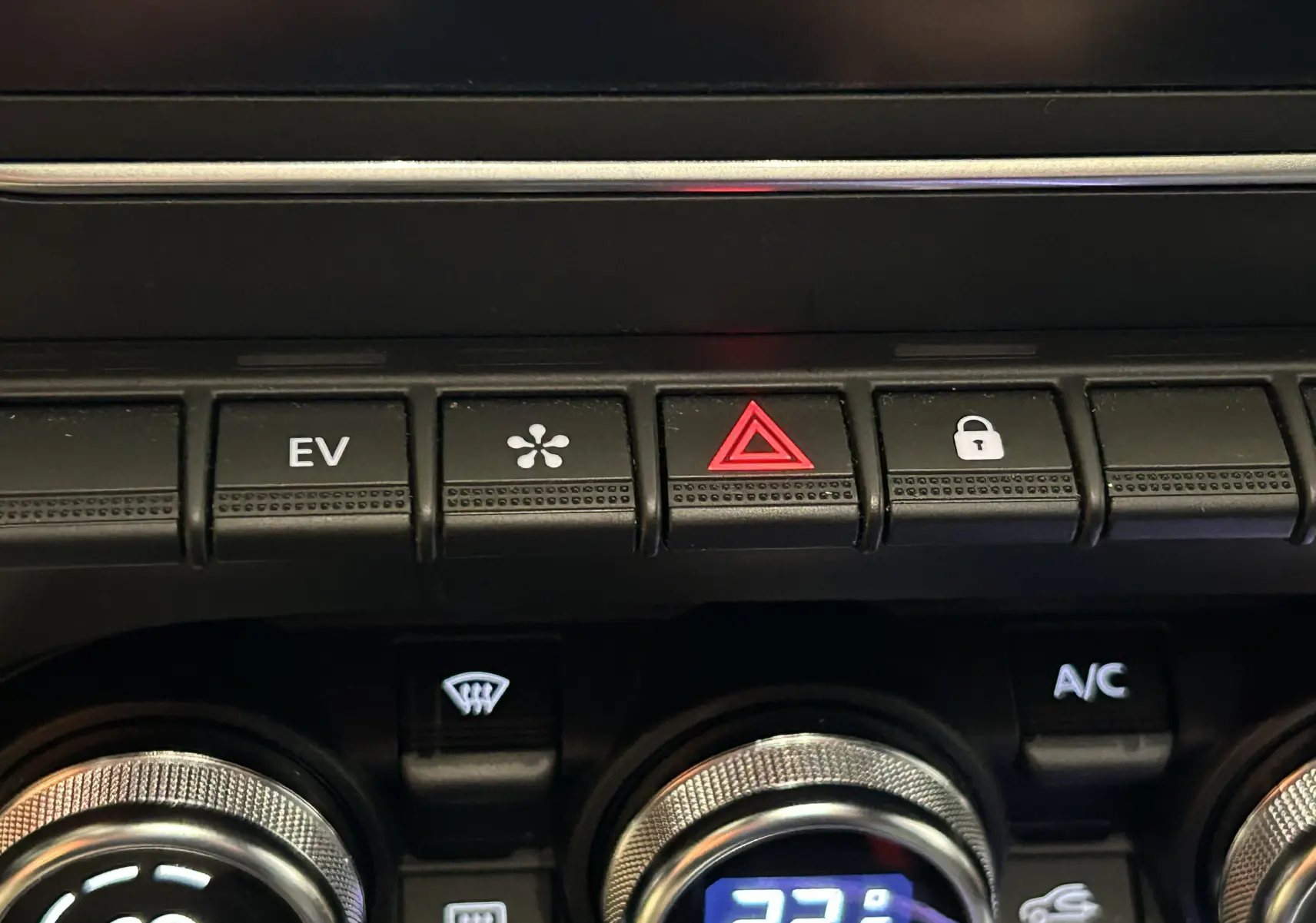 Gros plan sur les commandes centrales de la Renault Clio V E-TECH 145ch, boutons EV, hazard et verrouillage visibles.