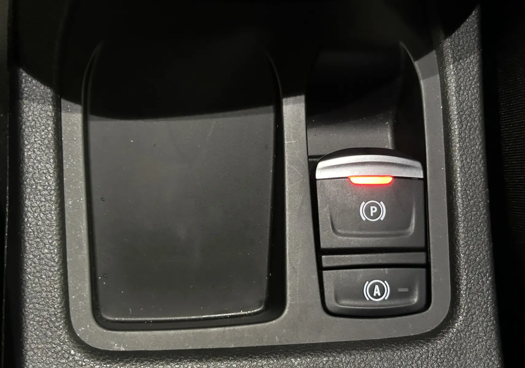 Gros plan sur la console centrale de la Renault Clio V E-Tech, montrant les boutons de frein à main électronique et arrêt/start.