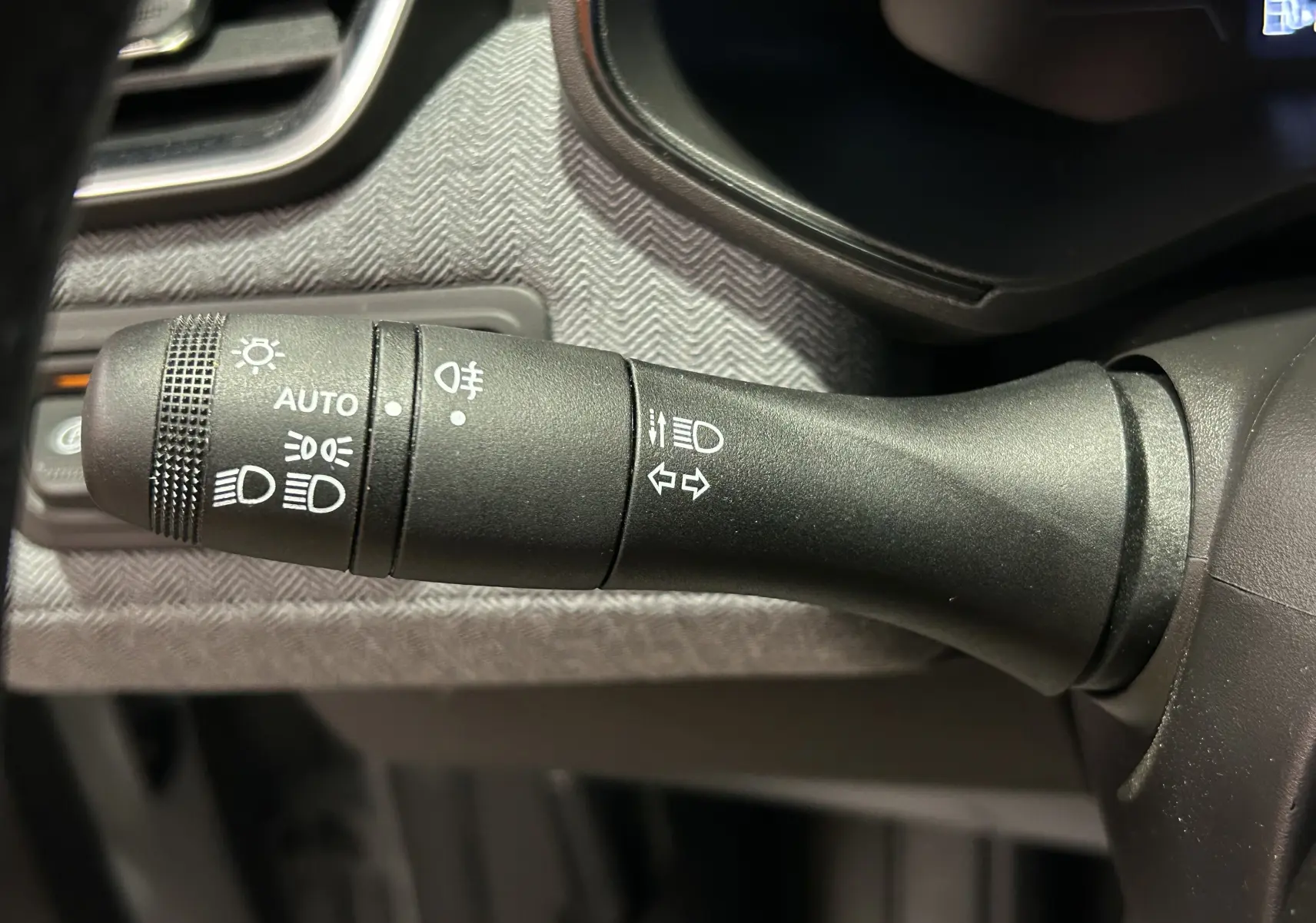 Gros plan sur la commande des feux et clignotants dans l’habitacle de la Renault Clio V gris Rafale Métal.