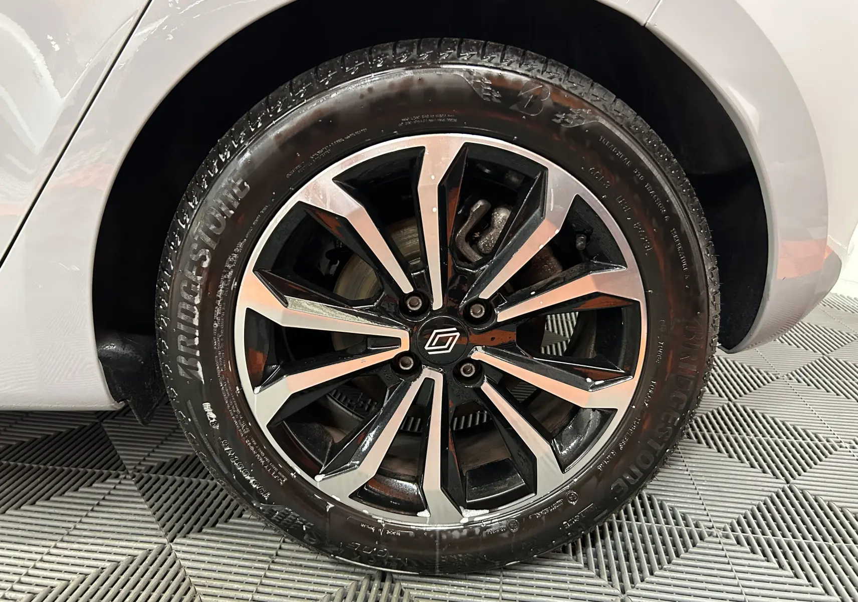 Gros plan sur la roue avant gauche de la Renault Clio V gris Rafale métal avec jante alliage noire et argentée.