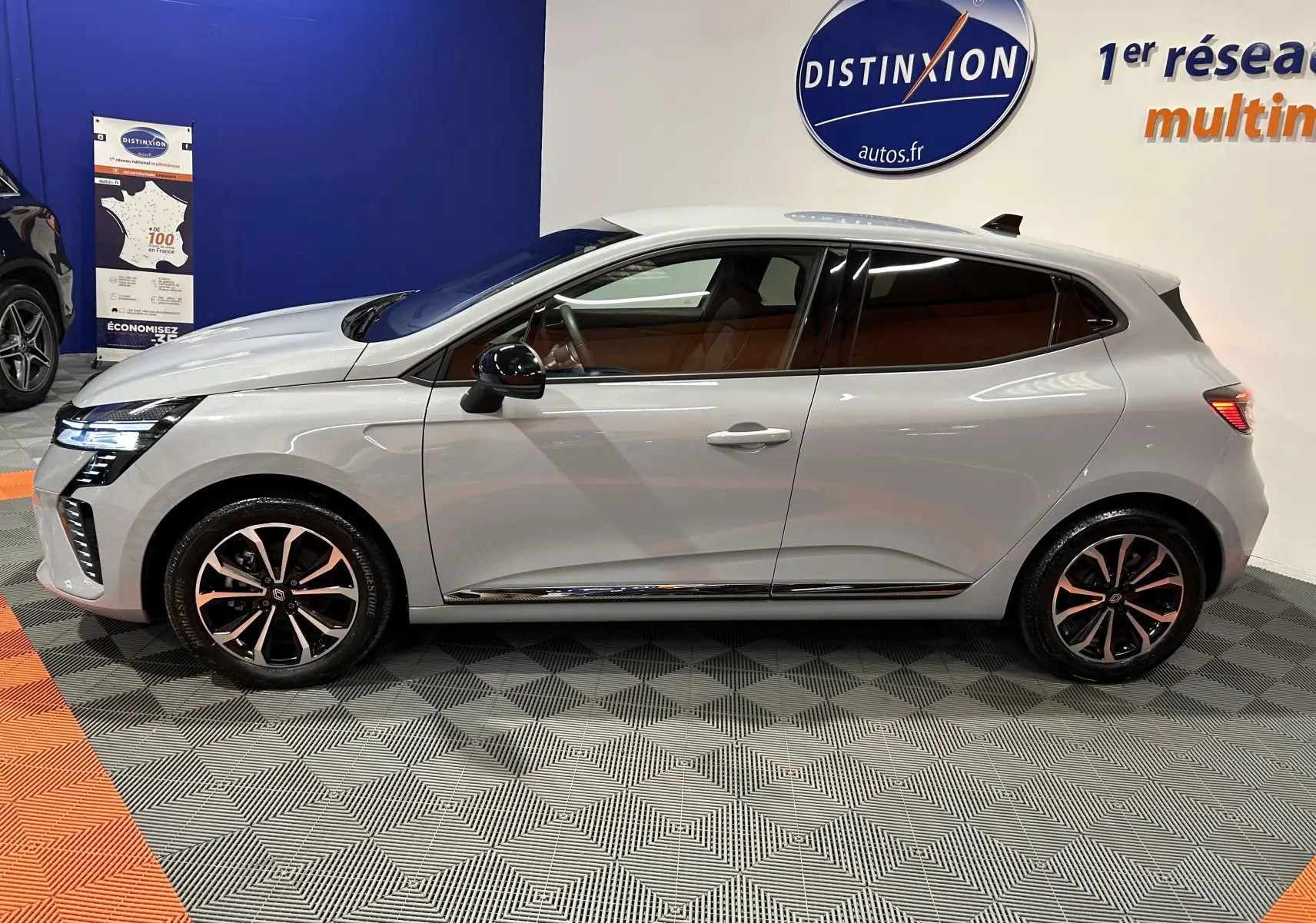 Profil droit d'une Renault Clio V E-Tech gris Rafale métal, avec jantes alliage noires et détails chromés visibles.