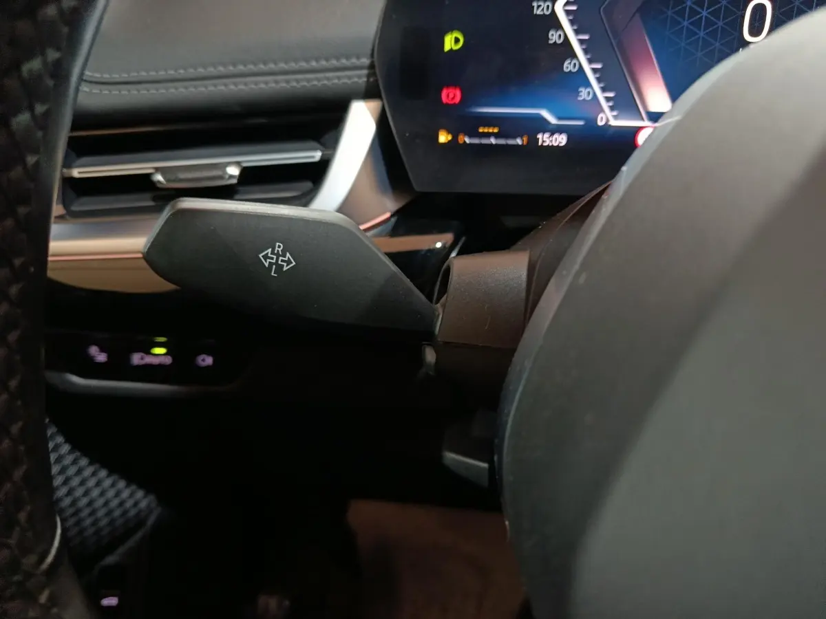 Gros plan sur le commodo de clignotant noir dans l’habitacle du BMW X1 xDrive23i M Sport 2023, tableau de bord digital visible.