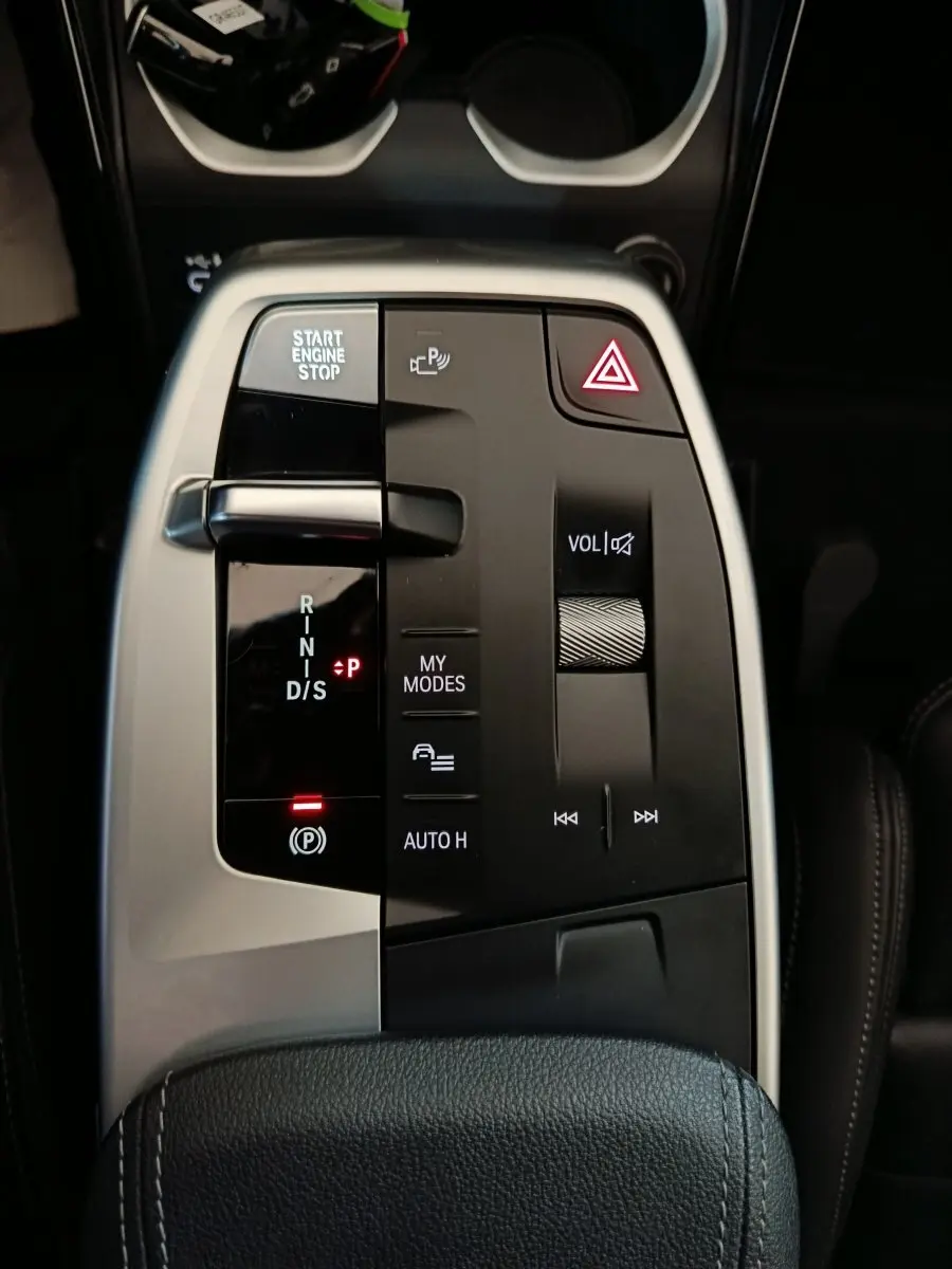 Gros plan sur la console centrale noire et argentée du BMW X1 xDrive23i M Sport avec commandes de boîte auto et volume.
