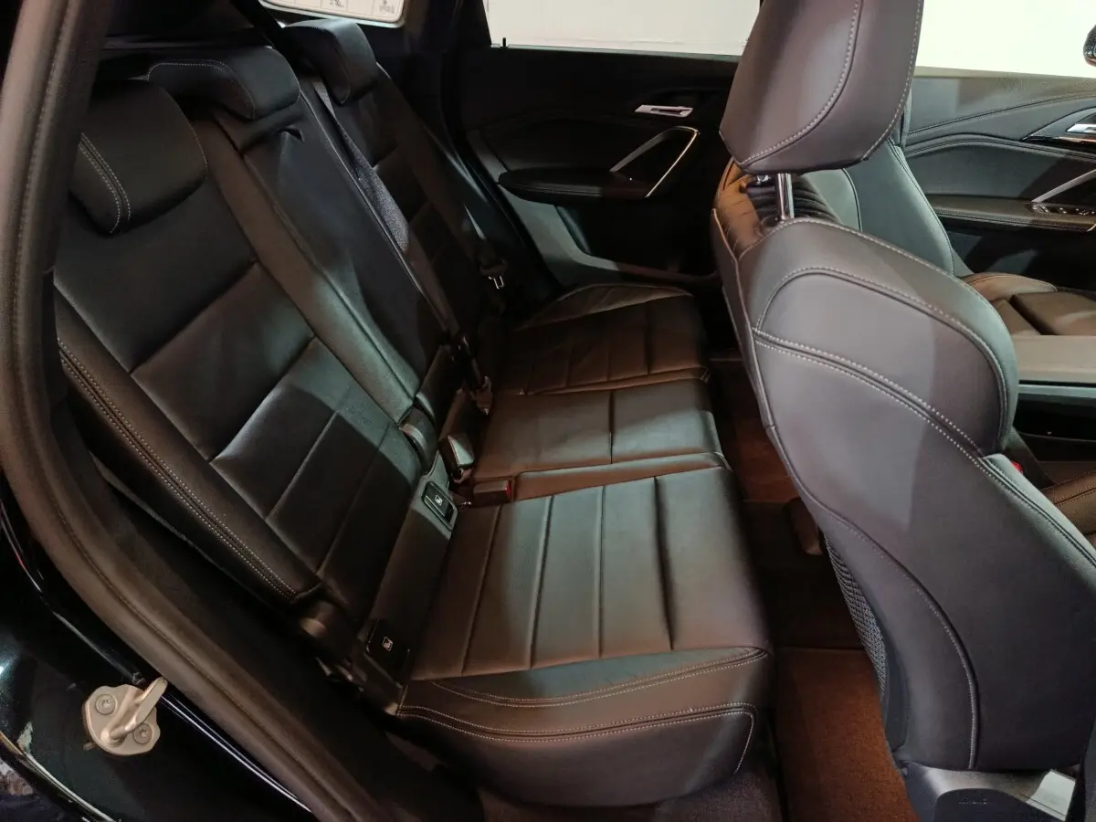 Vue intérieure côté arrière gauche montrant la banquette noire en cuir du BMW X1 xDrive23i M Sport 2023.