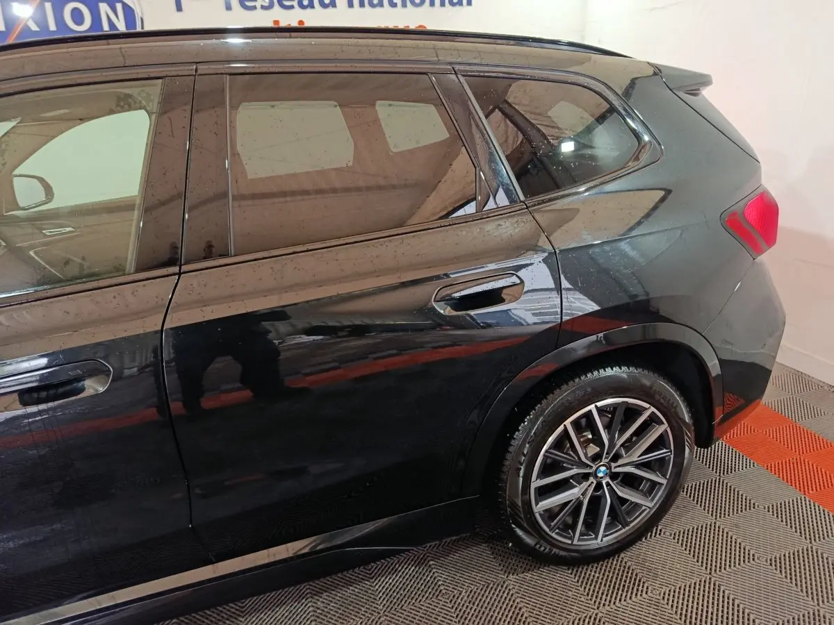 Vue latérale droite d'un BMW X1 xDrive23i M Sport noir, mettant en valeur les jantes alliage et les vitres teintées.