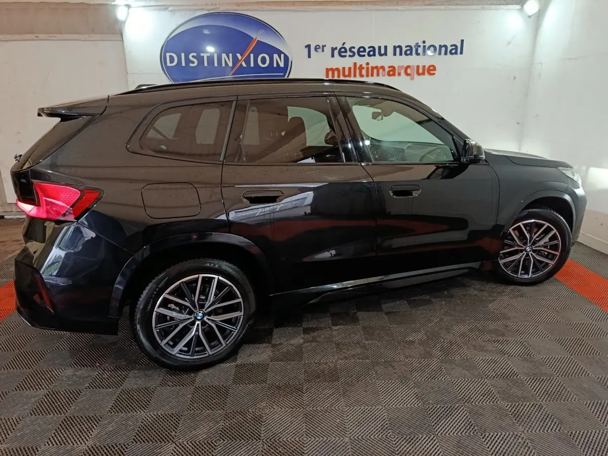 BMW X1 xDrive23i M Sport noir vue de profil côté gauche, avec jantes alliage et feux arrière LED allumés.