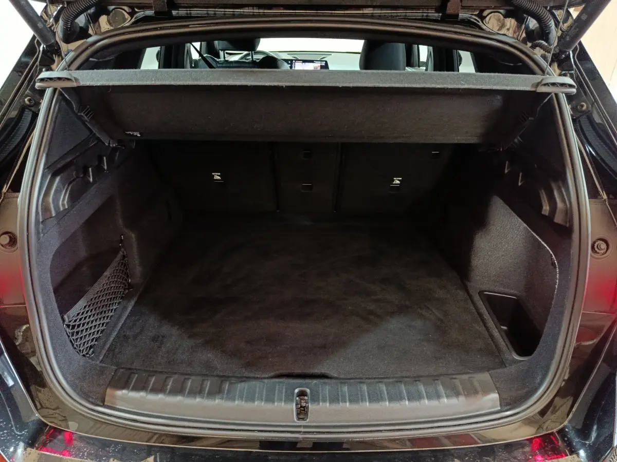 Coffre ouvert vu de l'arrière d'un BMW X1 noir 2023, montrant l'espace de chargement et la tablette de séparation.
