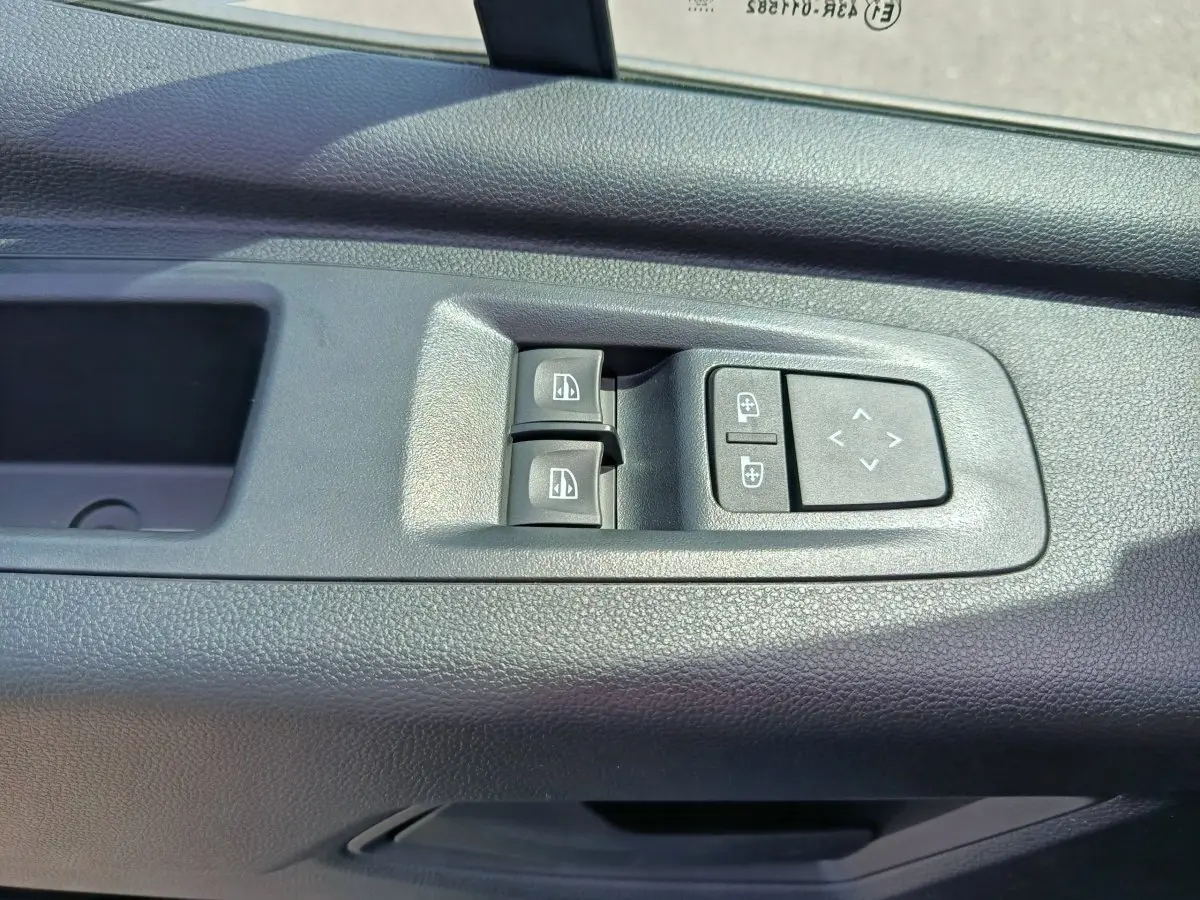 Gros plan sur les commandes de réglage des vitres et des rétroviseurs côté gauche du Renault Master blanc.
