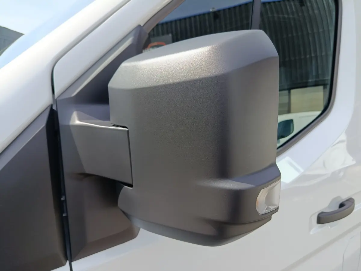 Gros plan sur le rétroviseur droit noir mat du Renault Master blanc, avec porte et vitre partiellement visibles.