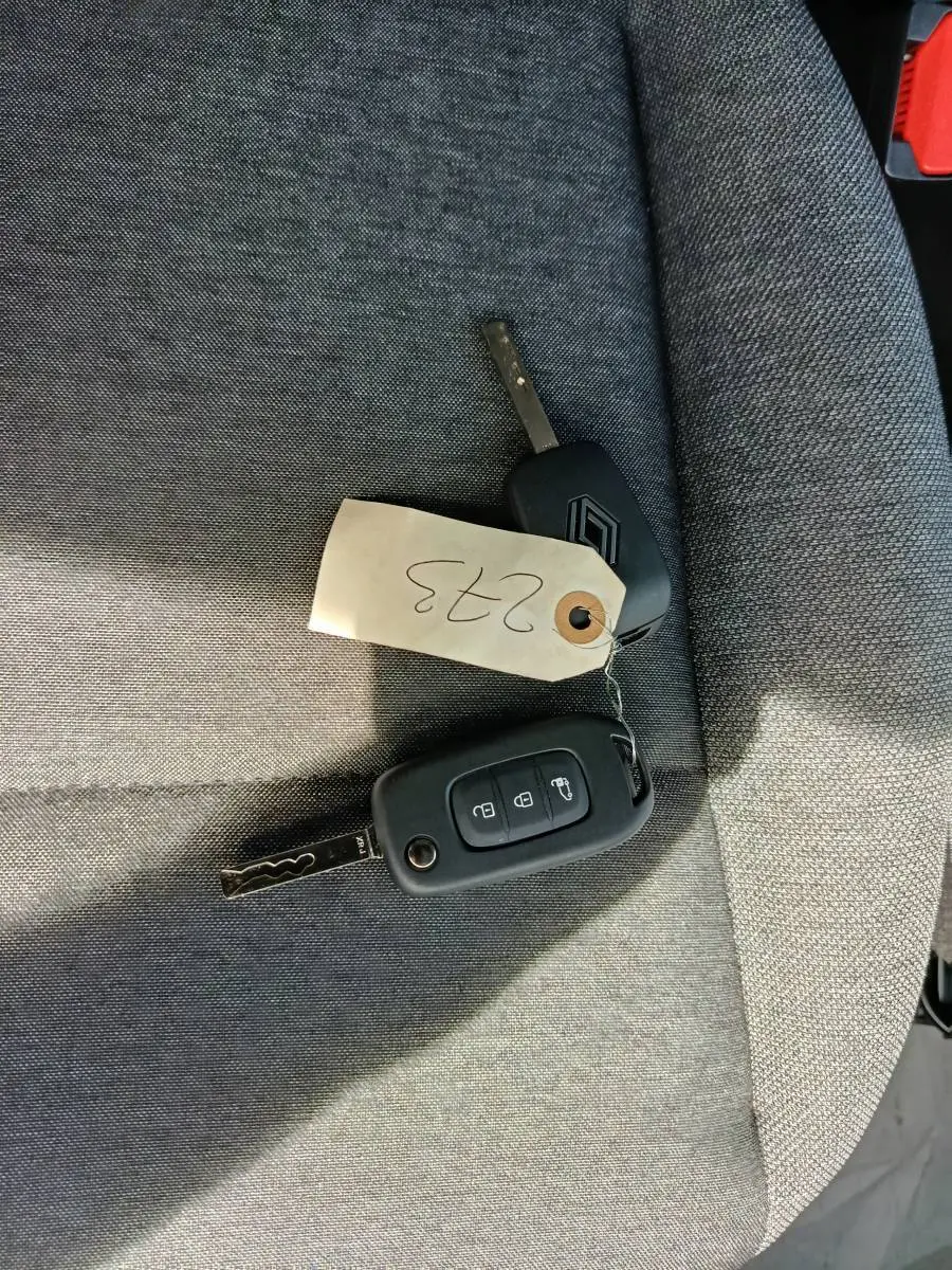 Clé et télécommande Renault Master posées sur un siège tissu gris, vue en plongée rapprochée.