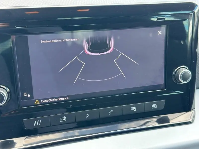 Écran tactile intérieur du SEAT Arona 2025 montrant l'aide au stationnement avec interface noire brillante.