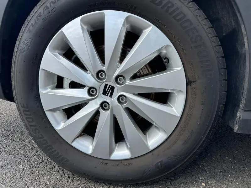 Gros plan sur la jante alu argentée avec logo SEAT, montée sur pneu Bridgestone d’un SEAT Arona blanc.