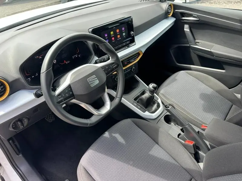Intérieur SEAT Arona 2025 vu côté conducteur, volant cuir multifonction, sièges tissu gris et console avec boîte manuelle.