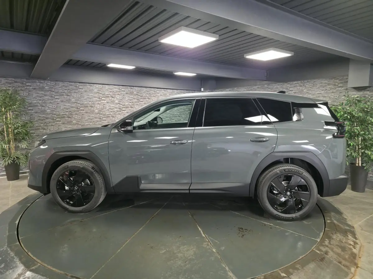 Vue de profil côté gauche d'un Citroën C5 Aircross 2026 vert métallisé avec jantes alliage noires en showroom.