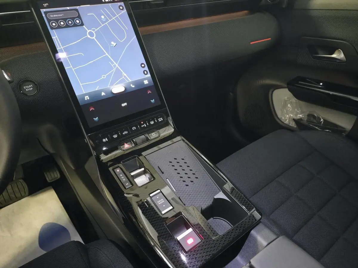 Vue intérieure centrée sur la console centrale noire brillante avec écran tactile vertical et sièges tissu bleu du Citroën C5 Aircross.
