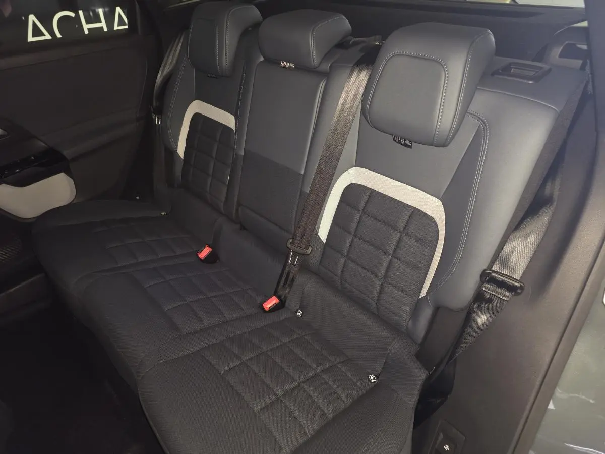 Vue intérieure sur la banquette arrière noire et grise du Citroën C5 Aircross 1.2i Hybride 2026 avec ceintures visibles.
