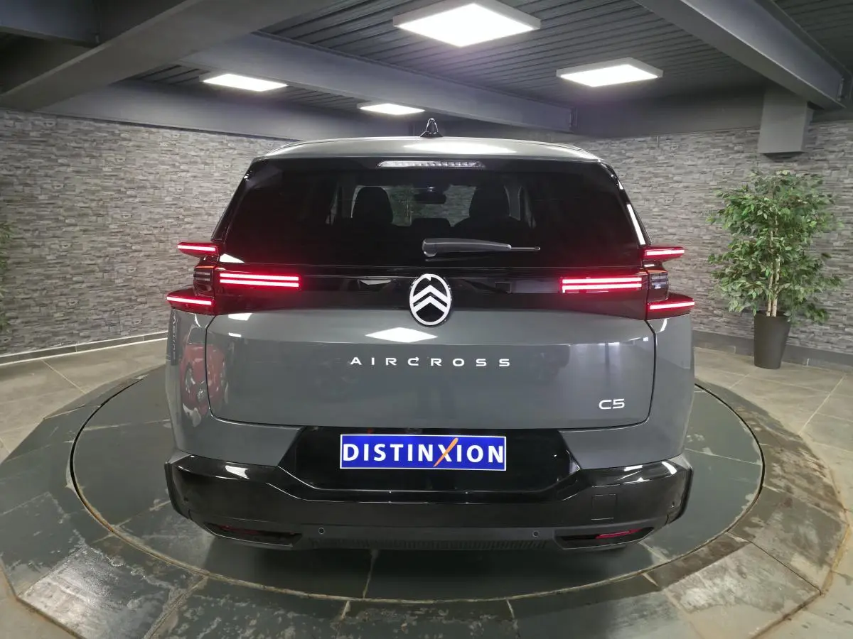 Vue arrière d'un Citroën C5 Aircross gris métallisé avec feux arrière LED horizontaux et logo central lumineux.