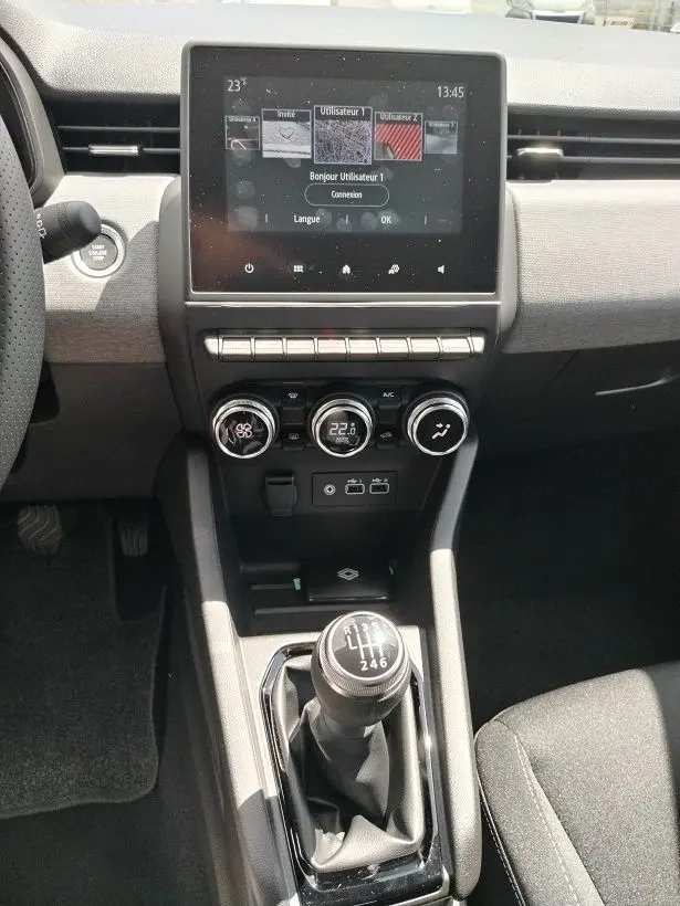 Vue intérieure centrée sur la console centrale de la Renault Clio V TCE 90 Evolution, avec écran tactile et levier de vitesse manuel.