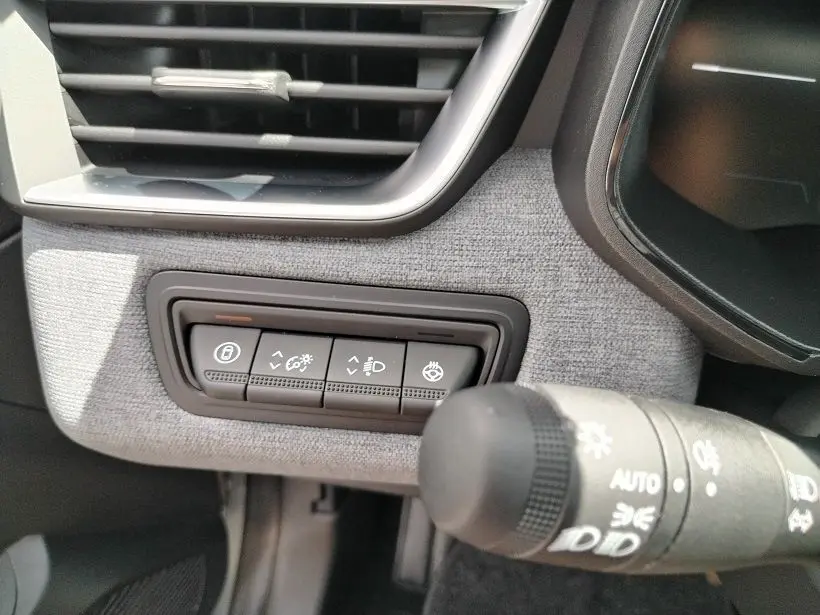 Gros plan sur les commandes d’éclairage et de réglage du tableau de bord gris clair de la Renault Clio V TCE 90 Evolution.