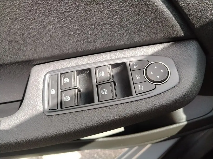 Gros plan sur les commandes de lève-vitres et rétroviseurs côté gauche intérieur de la Renault Clio V gris Rafale.